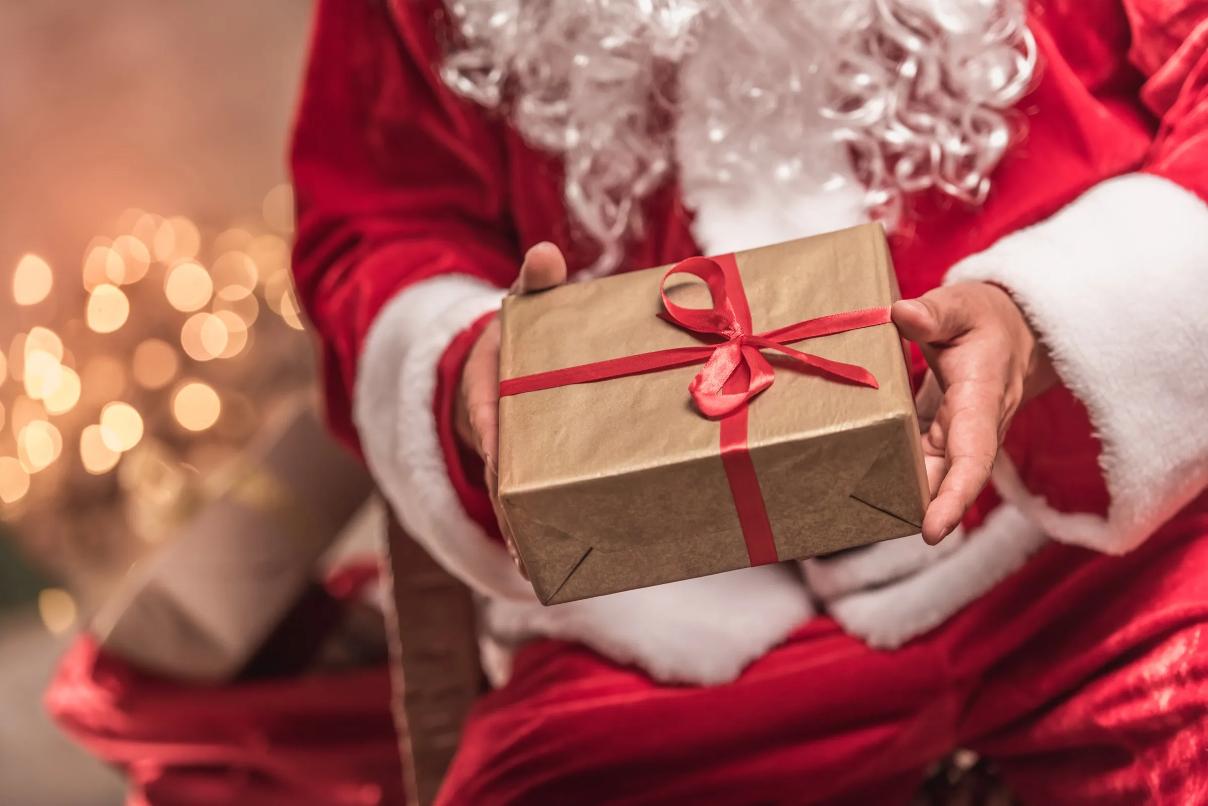 Santa Claus sosteniendo un regalo envuelto con listón rojo