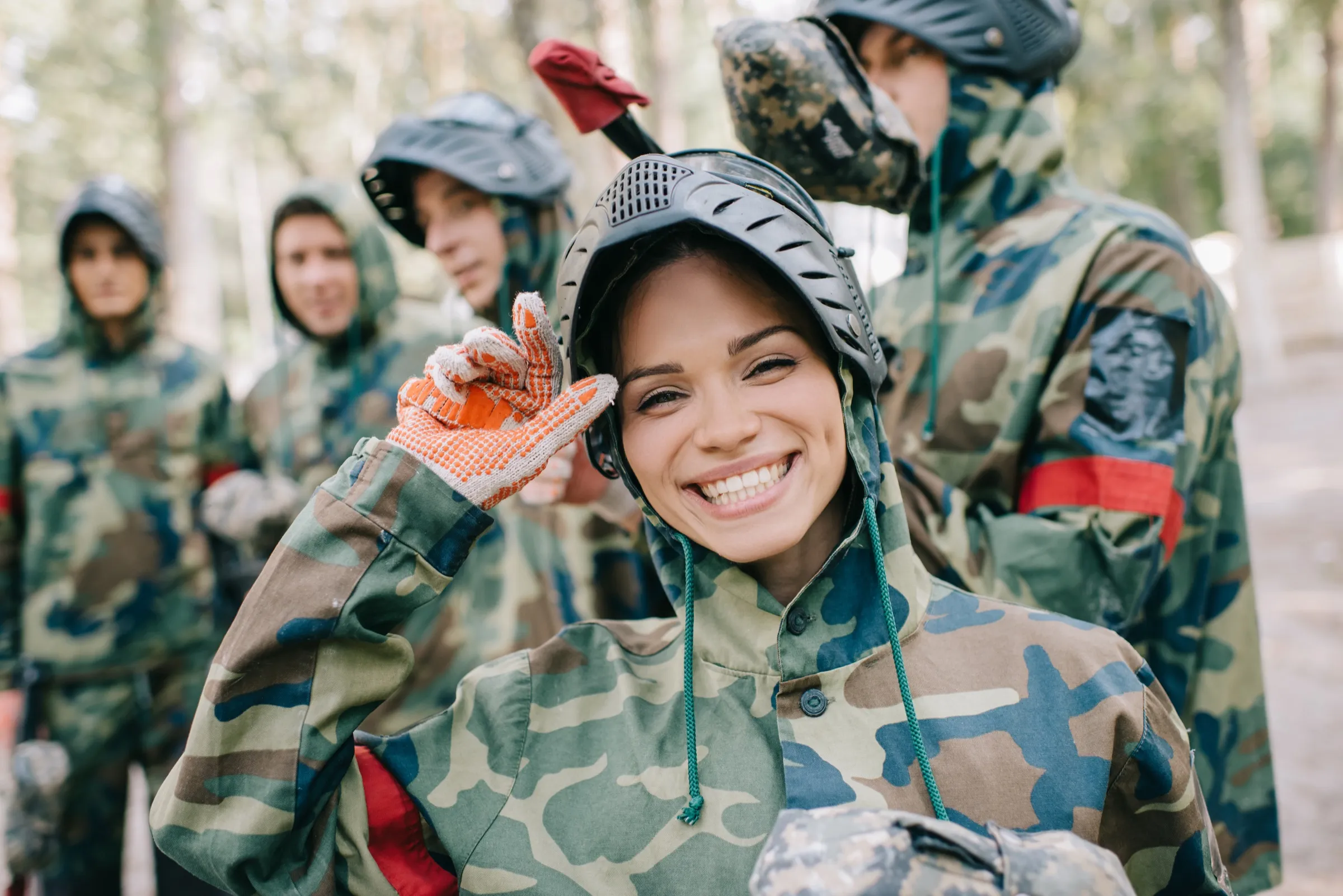 Grupo sonriente con equipo de gotcha en el bosque